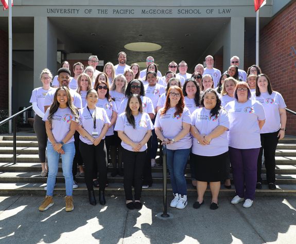 A group photo of people wearing matching purple shirts